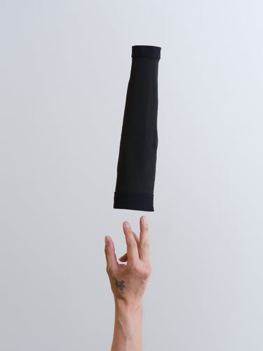 Black arm sleeve being held out towards a hand on a light gray background